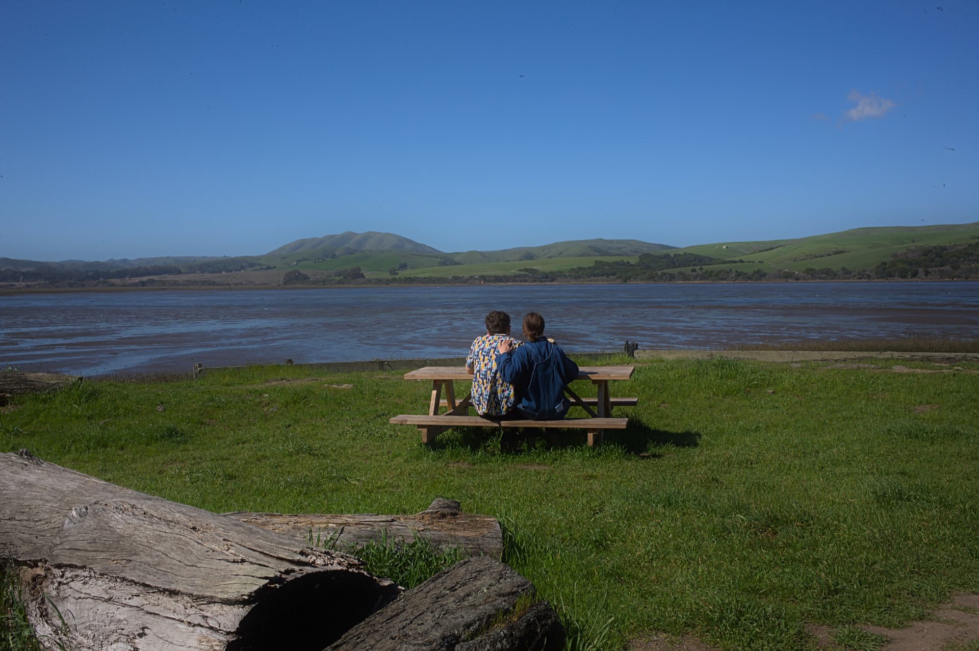 Couple sitting at a picnic table overlooking a bay