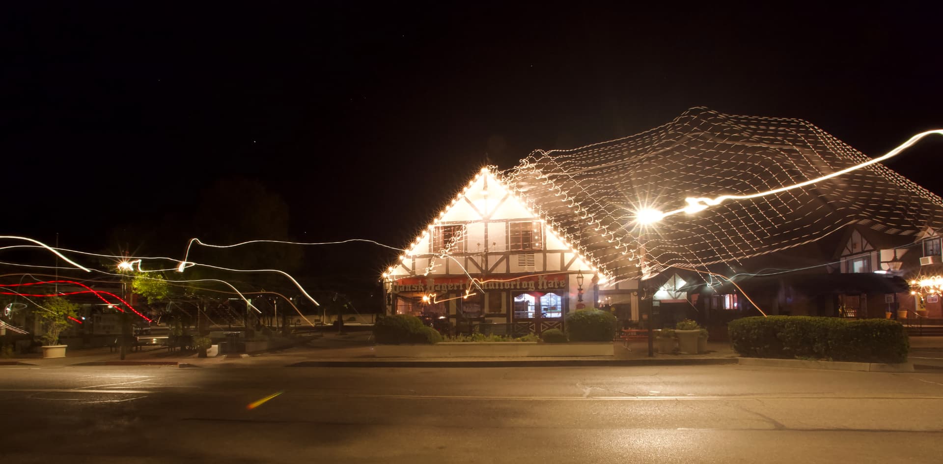 Long-exposure light trails over a lit village storefront at night